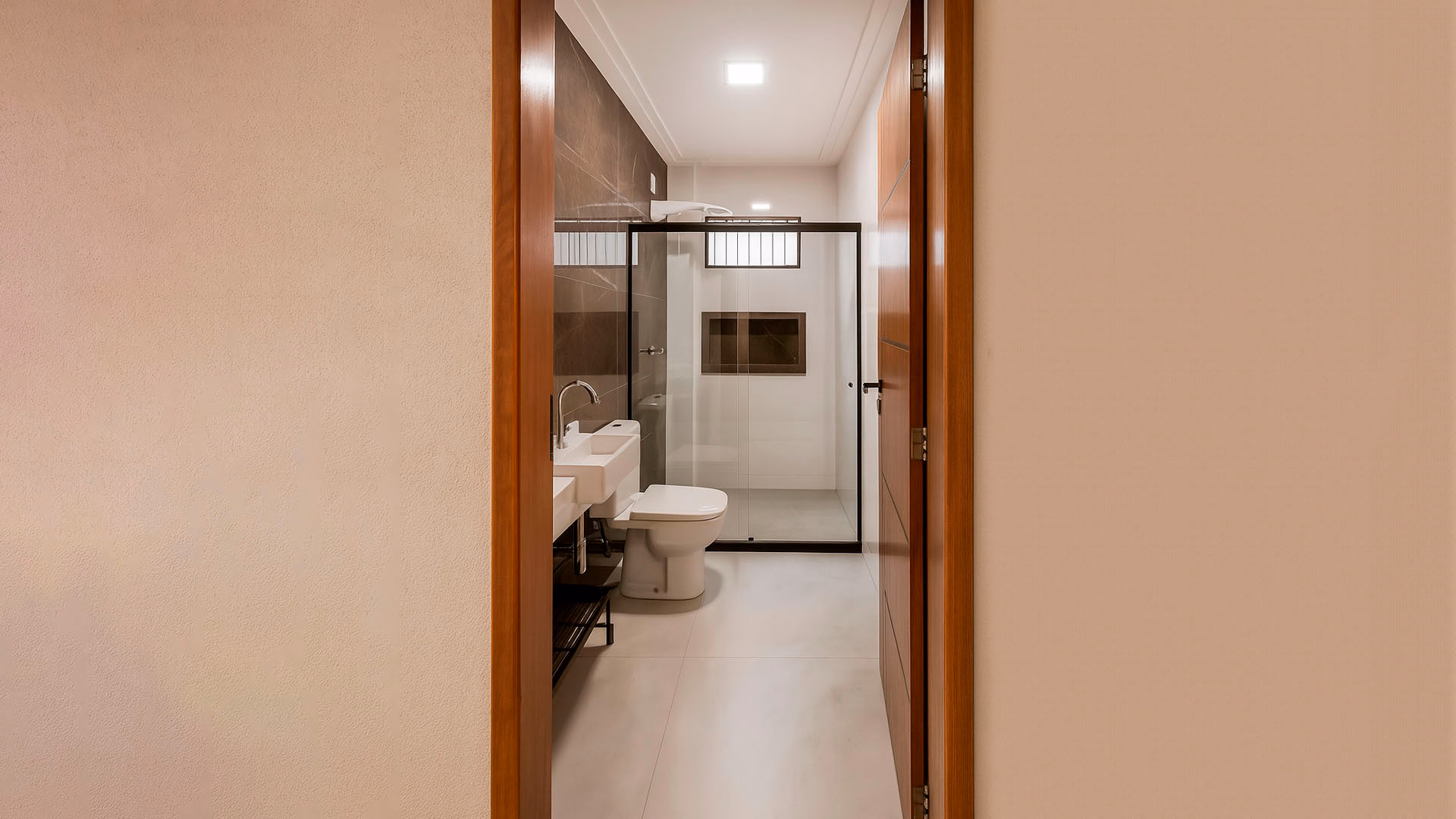 Banheiro reformado com revestimento de luxo, nicho embutido e iluminação planejada, exemplificando acabamento fino