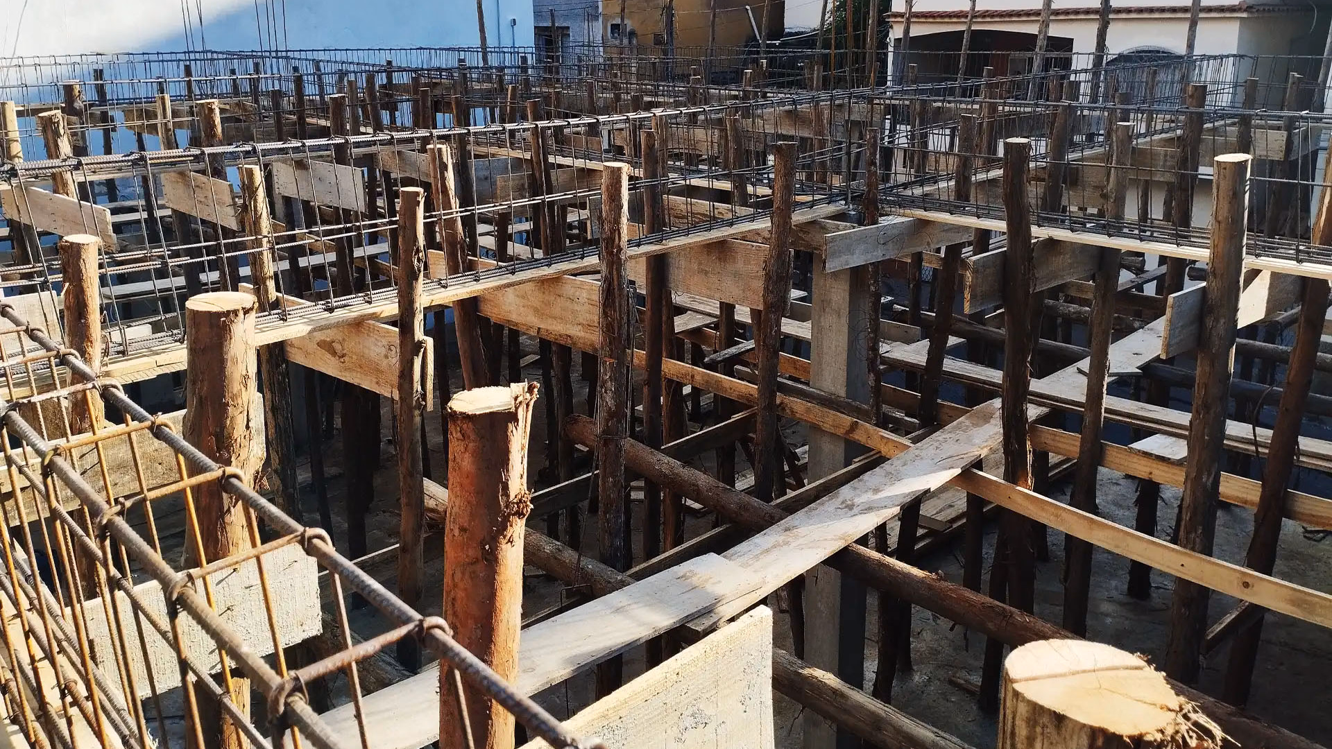 Estrutura de vigamento armado em madeira e ferro, demonstrando a fase inicial robusta de uma fundação comercial
